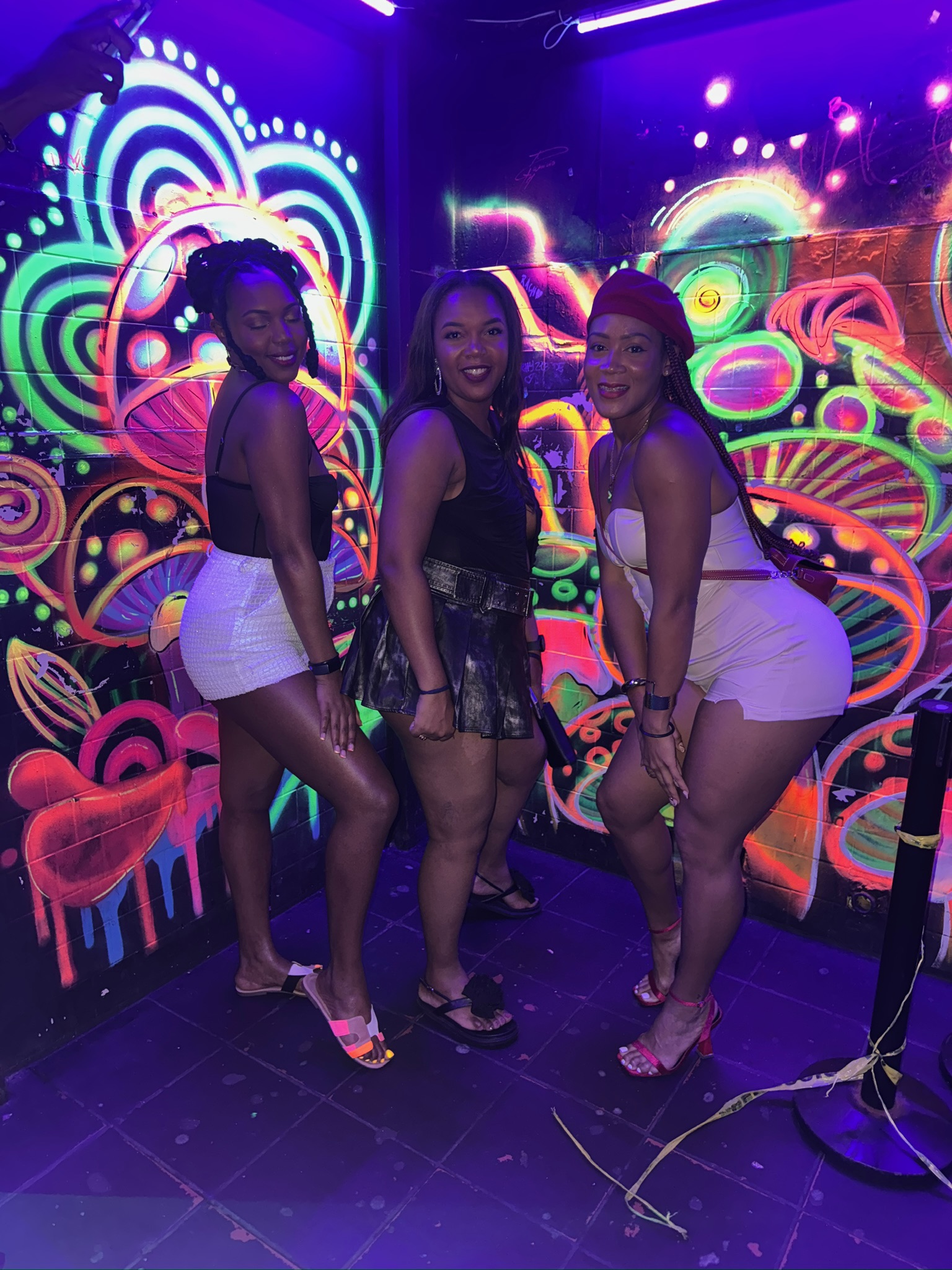 Guests beside the colourful neon mural at Chupitos